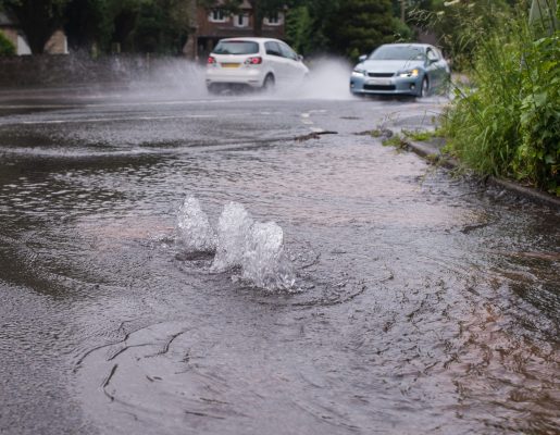 Cars driving through flooded road caused by burst water main.