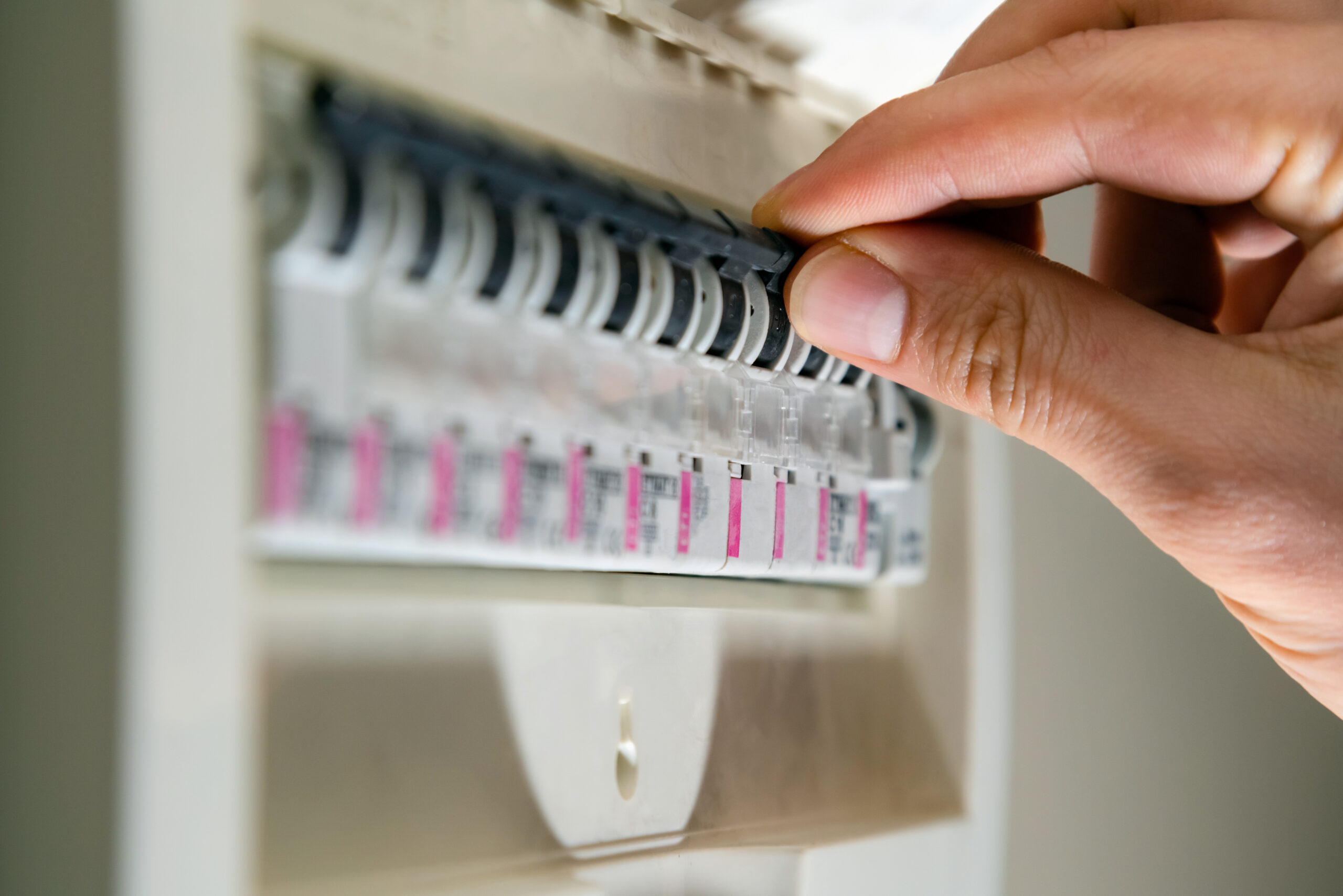 Hand switching off a fuse in a fuse box.