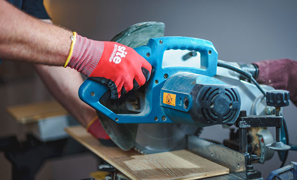 Tradesman using a circular saw to cut new flooring.