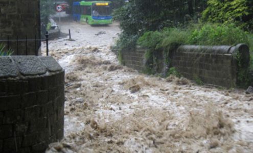 Server flash flooding running down a small lane towards a bus on the highway.