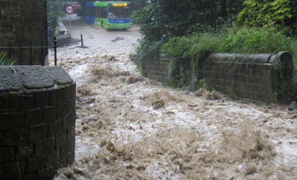 Server flash flooding running down a small lane towards a bus on the highway.
