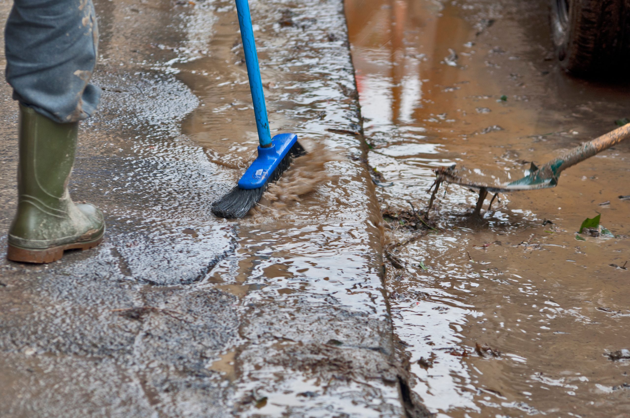 Cleaning the streets after flooding with a shovel and a brush.