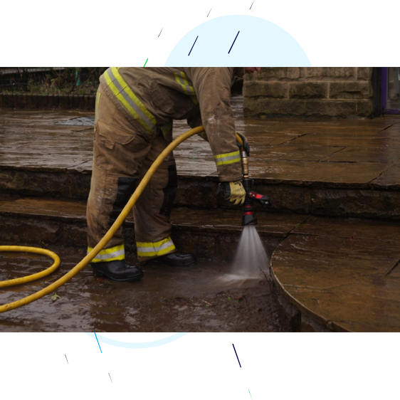 Firefighter hosing down flood residue.