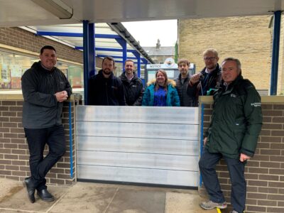 The Environment Agency  project team and one of the flood barriers installed at Burnley Road Academy 