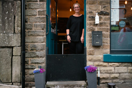 Blue Tea Pot in Mytholmroyd. Owner stands with flood door. Flood support for businesses.