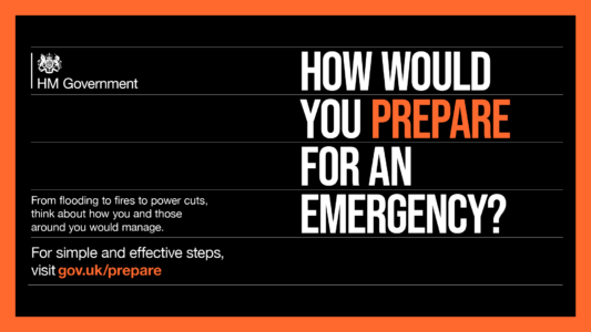 An advertisement from HM Government with a bold question in white text on a black background that reads ‘HOW WOULD YOU PREPARE FOR AN EMERGENCY?’ Below, in smaller font, the ad provides guidance stating ‘From flooding to fires to power cuts, think about how you and those around you would manage.’ It encourages simple and effective preparation with a call to action: ‘For simple and effective steps, visit gov.uk/prepare’. The website is highlighted in white against an orange strip at the bottom.