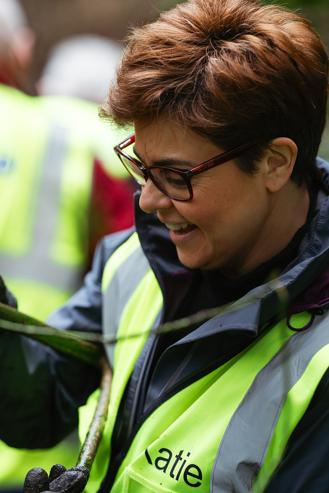 A Slow the Flow volunteer wearing a high-visibility vest holding a branch.