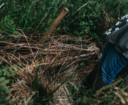 Long sticks piled high to create a leaky dam. A person stood next to the pile.