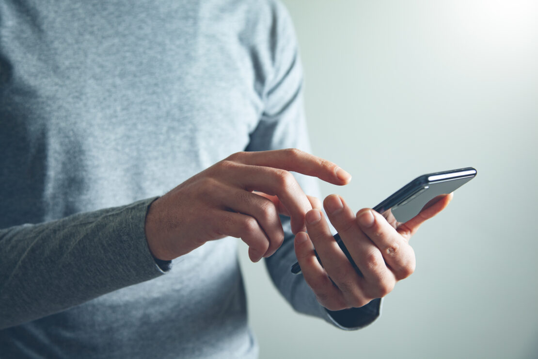 Person holding a smart phone and points towards it