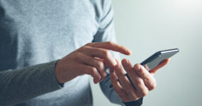 Person holding a smart phone and points towards it