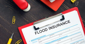 Red clip board with paper saying flood insurance
