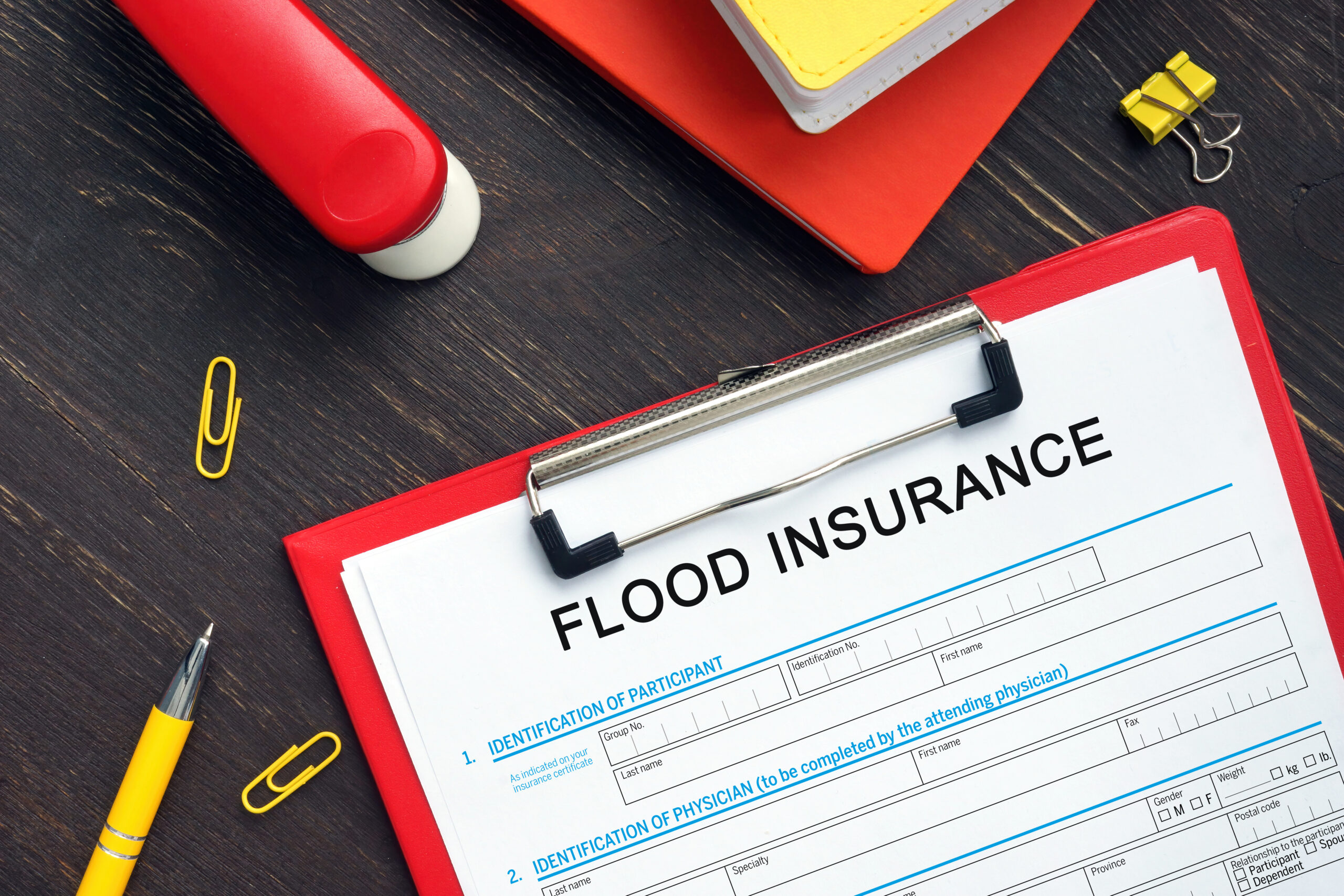 Red clip board with paper saying flood insurance