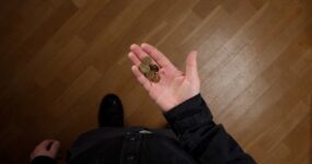 Person holding a small amount of scattered metal coins in an open palm.